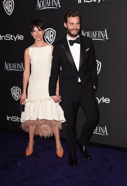 Imagen del actor Jamie Dornan, e intérprete de Christian Grey de 50 sombras de Grey, muy enamorado de su mujer Amelia Warner, en los golden Globe Awards, de la mano juntos 