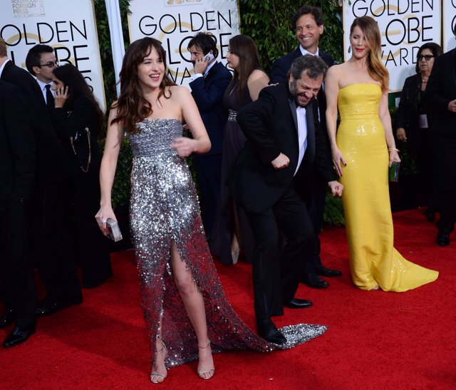 Foto de Dakota Johnson en los Golden Globe Awards muerta de la risa, cuando la pisan su vestido de gran cola en broma