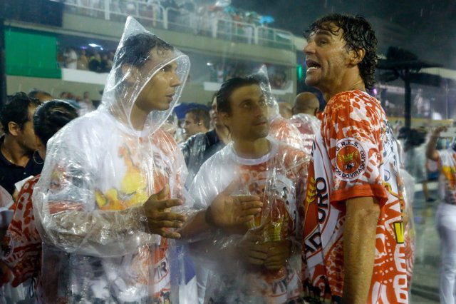 David Ferrer y Rafa Nadal con Gustavo Kuerten con unos chubasqueros transparentes resguardándose de la fuerte lluvia durante el desfile  en el Carnaval del Brasil. Empapados por completos