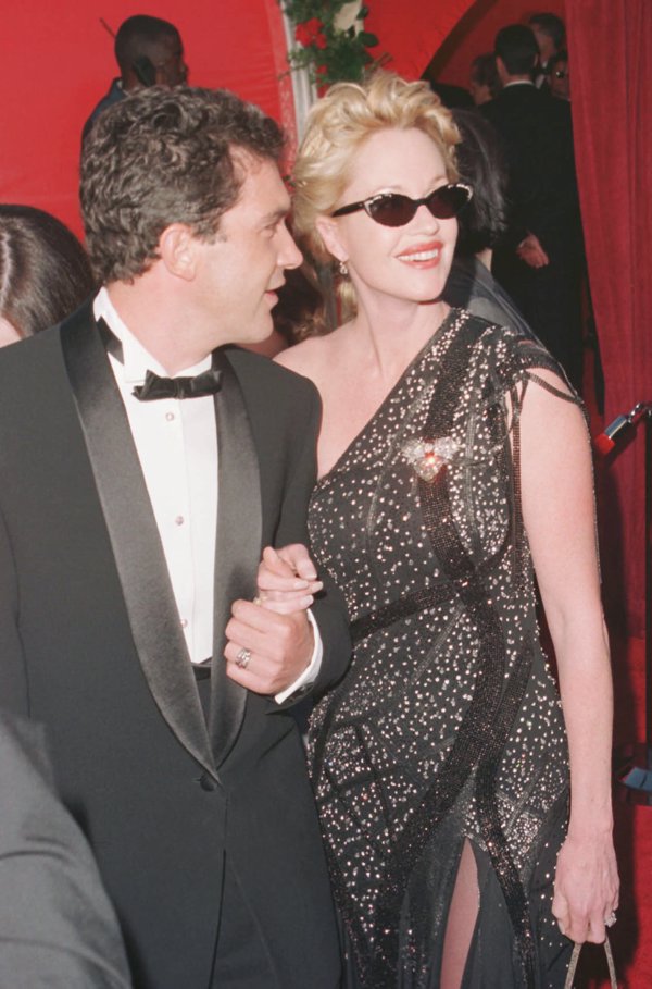 fotografía de Melanie Griffith y Antonio Banderas cuando ella era nominada por Armas de mujer en 1998. Melanie iba con gafas de sol y un vestido en negro con incrustaciones en plata de tirante asimétrico y abertura lateral. Los dos riéndose