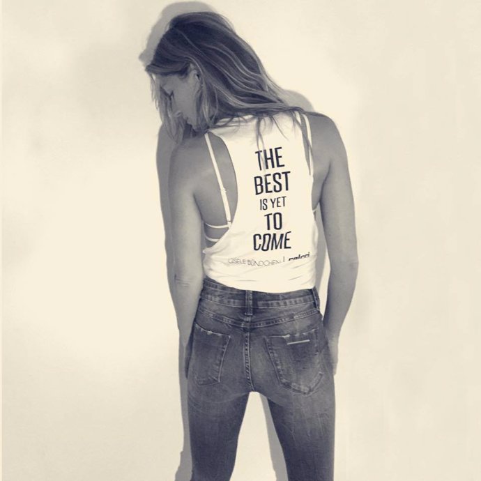 Gisele Bündchen en una foto en blanco y negro, de espaldas dejando la cara mirando a un lado con su melena rubia suelta, con unos vaqueros ajustados y una camiseta en la que se puede leer The Best is yet to come, o lo que es lo mismo Lo mejor está por venir