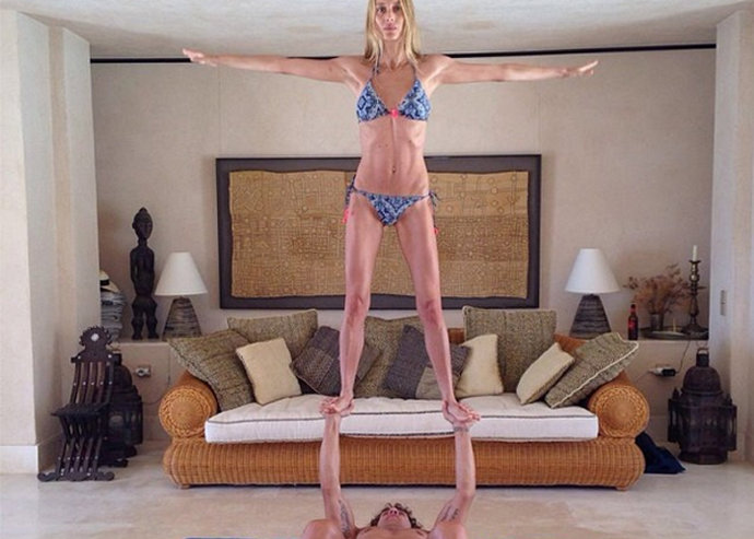 Carles Puyol y Vanesa Lorenzo practican yoga en pareja. Él en el suelo la sujeta con sus brazos en el aire (aeroyoga)