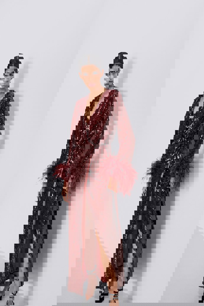 zara rompe con su vestido de lentejuelas largo, cruzado con plumas en burdeos