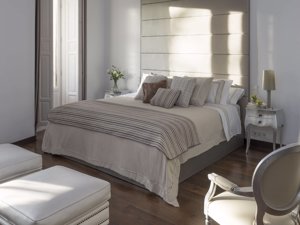 Carmen Borja propone una cama en tonos claros, con muchos cojines y siempre con un cubresomier