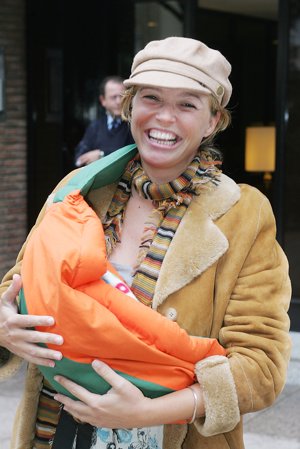 La presentadora Carolina Ferre tras ser mama con un alegre fular canguro en verde y naranja, lleva a su bebé con las dos manos
