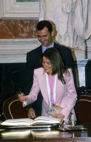 Letizia firmando en el libro del Congreso durante un almuerzo,ante la divertida mirada del Príncipe