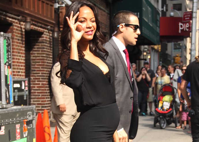 Zoe Saldana a mediados de su embarazo, espectacular vestida con camisa y falda lápiz en negro y stilettos a juego. La actriz hace con sus dedos la señasl de okey de lo más divertida