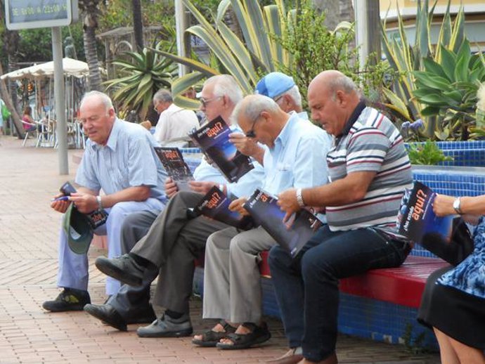 Un grupo de personas miran un folleto de Tenerife en La Playa de Las Canteras (G