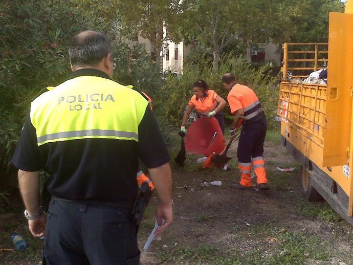 Efectivos de Lipasam retiran basuras ante la mirada de un Policía Local