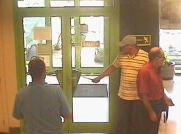 El atracador vigila la entrada de la entidad bancaria