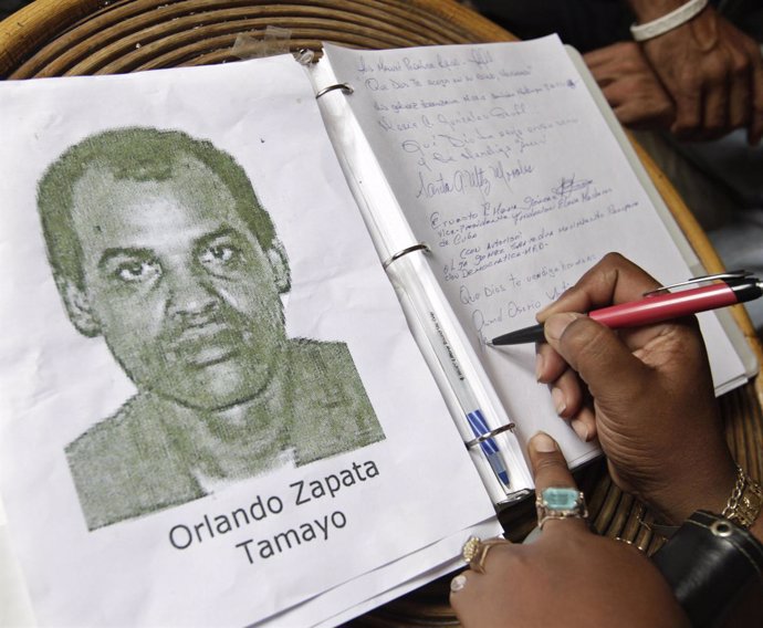 Una Mujer Firma En Un Libro De Condolencias Por La Muerte De Orlando Zapata.