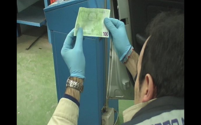 Un Agente Examina Uno De Los Billetes Falsificados.