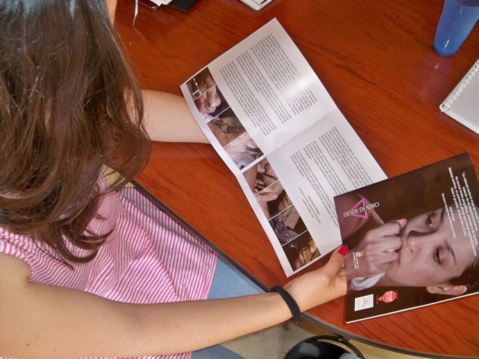 Una joven ojea el folleto de la exposición.