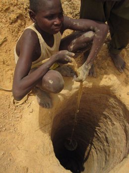 Niño extrayendo agua de un pozo