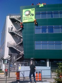 Activistas de Greenpeace se cuelgan de la sede de BP en Madrid para cambiar su logo por otro "teñido" de petróleo
