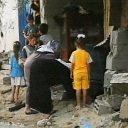 Mujer y niños palestinos entre ruinas