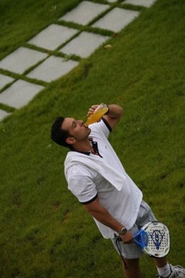 Un tenista se hidrata tomando una bebida. 
