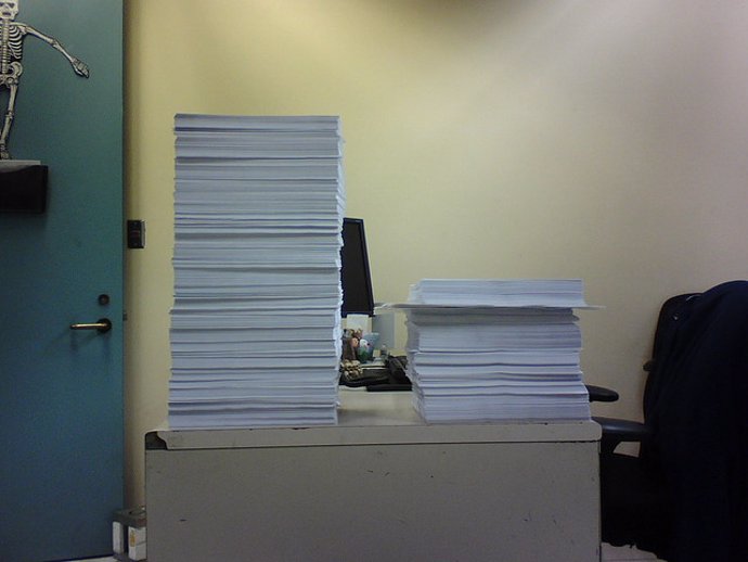 Montaña de documentos impresos en una oficina.