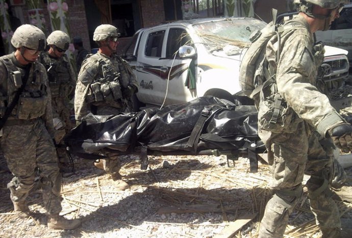 Soldados de la coalición transportan compañero muerto en Afganistan 
