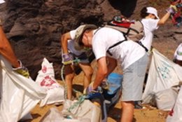 La imagen muestra a un grupo de voluntarios realizando tareas de limpieza en el 