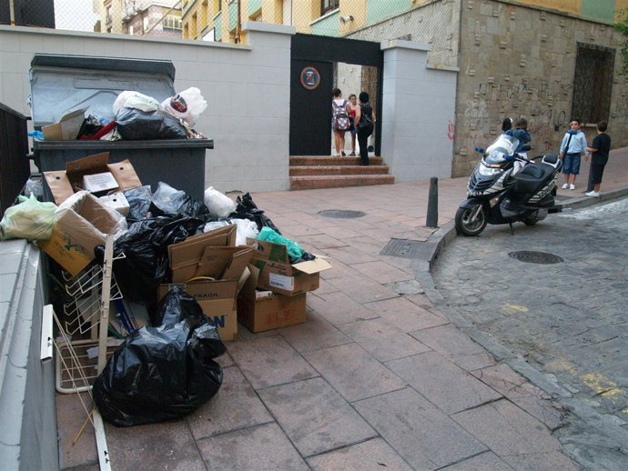 Entrada de un colegio concertado con los contenedores llenos delante