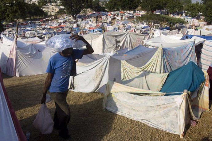 Un hombre carga con provisiones en un campamento en Haití