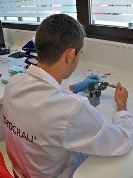 Un trabajador de Mozo-Grau mide un pieza de implante dental.