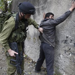 Soldado de Israel cacheando a un palestino en Gaza