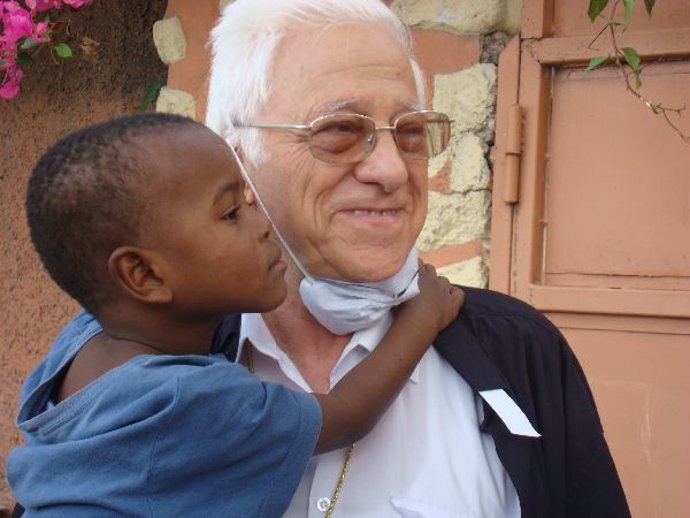 padre ángel fundador de Mensajeros de la Paz con un niño en Haití