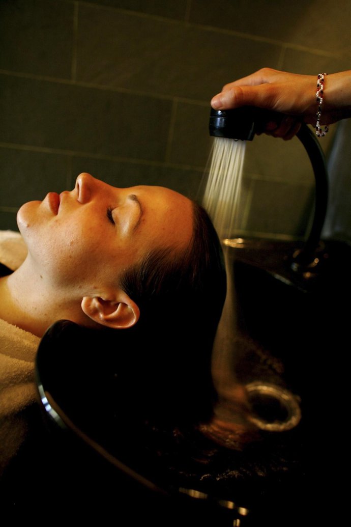 Mujer lavándose el pelo en la peluquería 