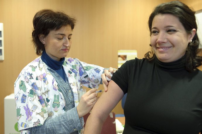 Sanitaria  vacunando de la gripe a una usuaria