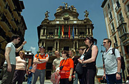 Varios turistas escuchan las explicaciones de un guía en Pamplona.