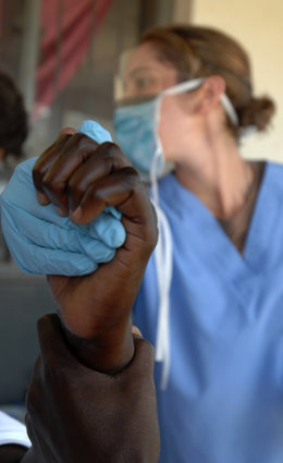 Una enfermera sostiene la mano de un paciente en África