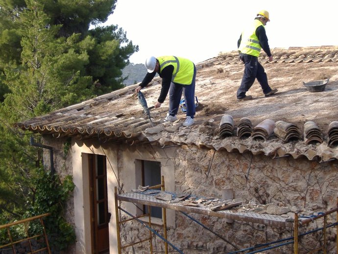 Dos operarios iniciando el derribo de un chalet en Llucalcari