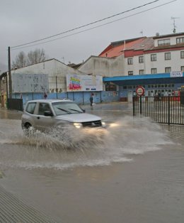 Un vehículo circulando por una vía inundada en el centro de Villaviciosa