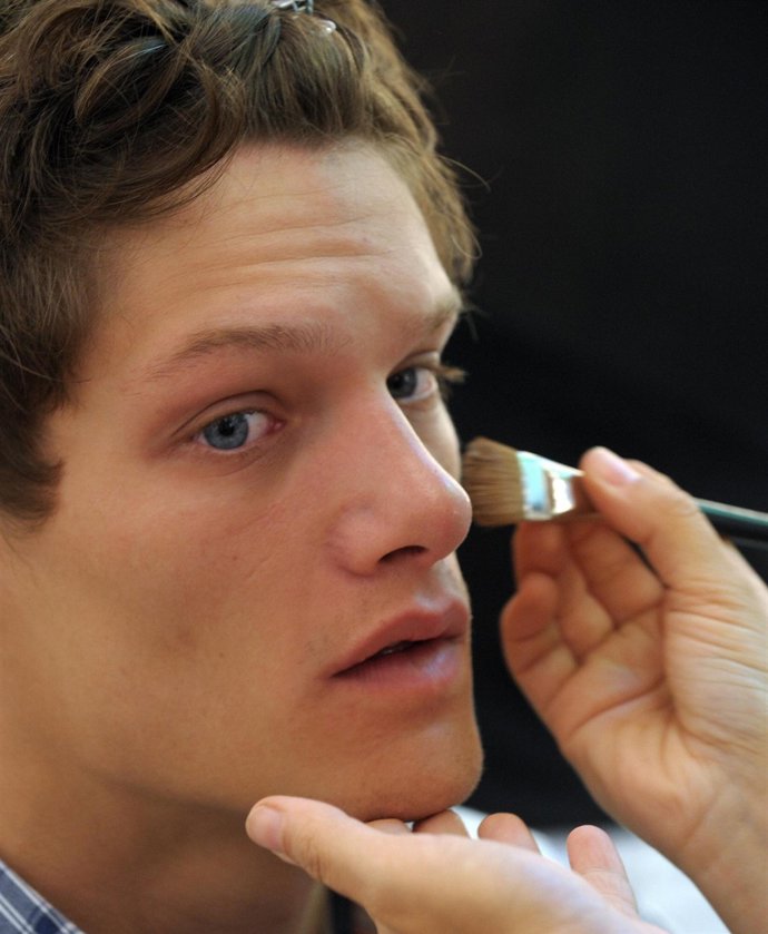 Un modelo masculino siendo maquillado 