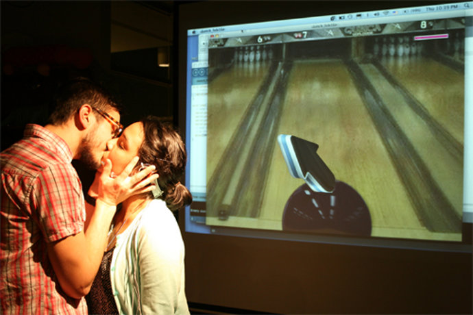 Una pareja se besa para hacer rodar la bola en el juego de bolos.