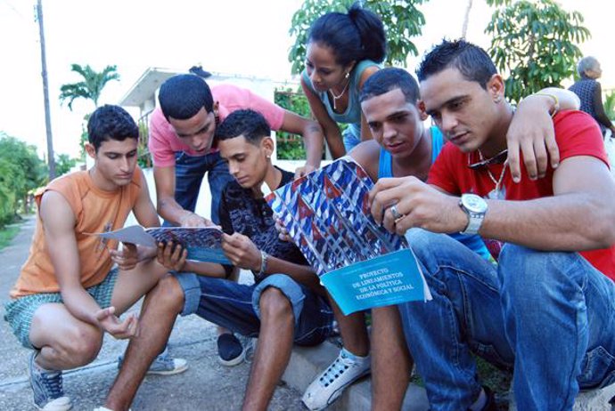 Jóvenes leyendo el proyecto sobre las reformas económicas en Cuba.