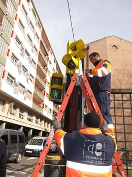Operarios municipales instalan las lámparas LED en un semáforo de la calle Albar