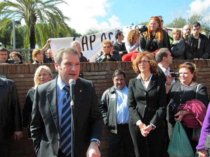 El alcalde, Jordi Hereu, durante el discurso, con una pancarta de los manifestan