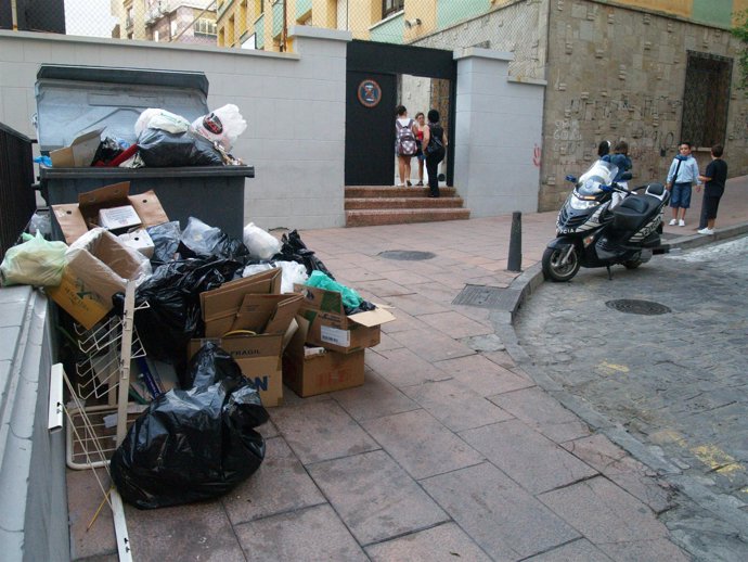 Entrada de un colegio concertado con los contenedores llenos delante