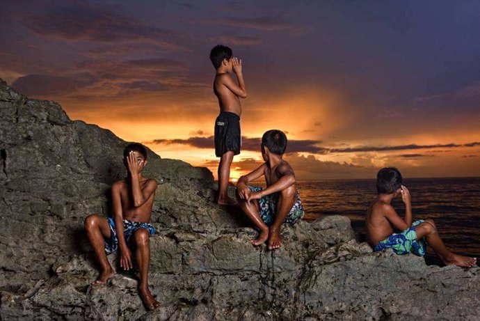 Niños asiáticos posan al atardecer en Puerto Galera, Filipinas, un paraíso natur