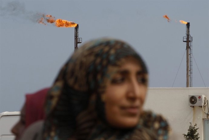 Una mujer camina frente a las torres petroleras de Libia