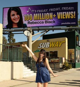 Rebecca Black Posando Delante De Un Anuncio Suyo