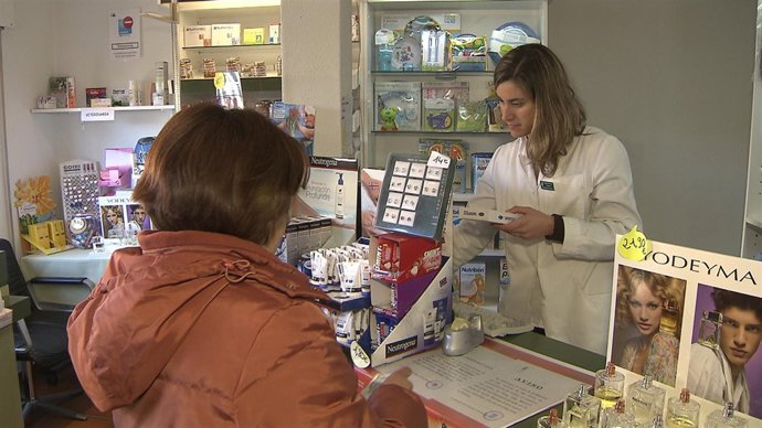 Una farmacéutica dispensa un medicamento a una usuaria