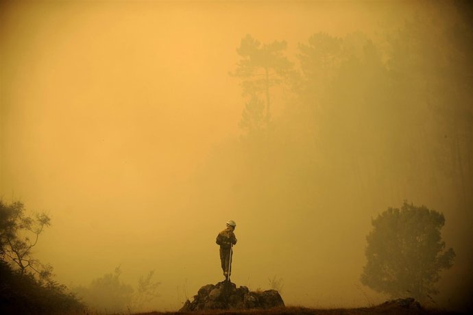 Members of the fire Galician brigade are seen around the area where a fire burns
