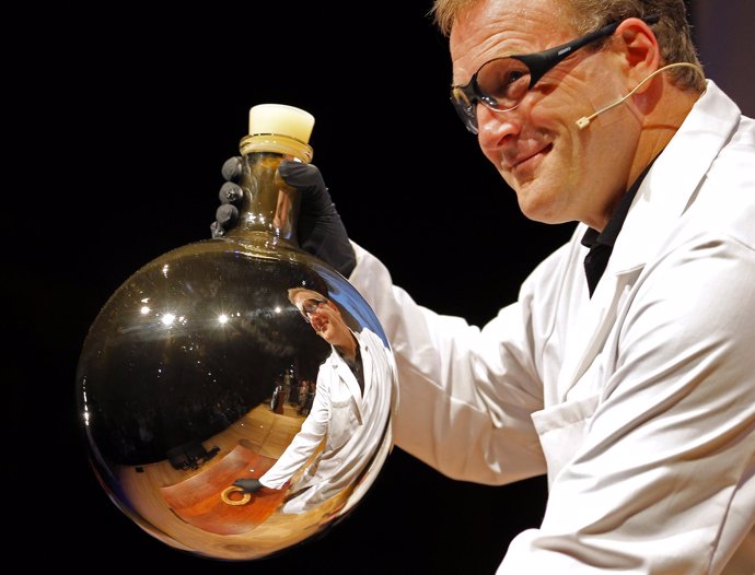 A Chemist Is Reflected In A Beaker After Mixing Chemicals That Gave The Beaker A