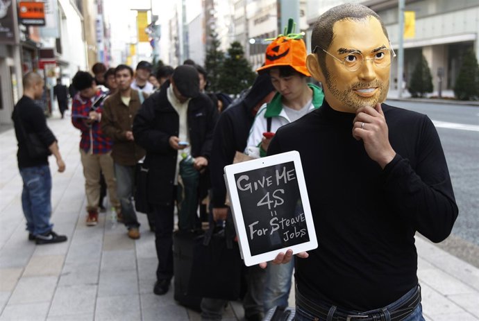 A Man Wearing A Mask Of Apple Founder Steve Jobs Stands In A Line To Buy An Ipho