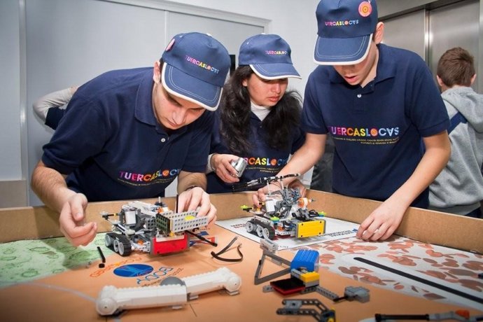 Tres integrantes del equipo de robótica trabajan en su proyecto.