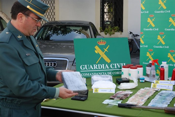 Un Agente Muestra Un Ladrillo De Cocaína, Junto Al Resto De Drogas Y Efectos Int